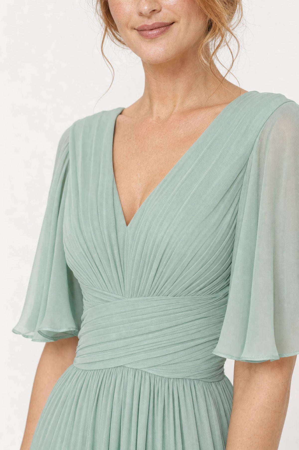 Gros plan sur le col en V plissé et la taille empire drapée de la robe demoiselle d'honneur vert sauge Rosalie, détail du tissu mousseline et des manches papillon