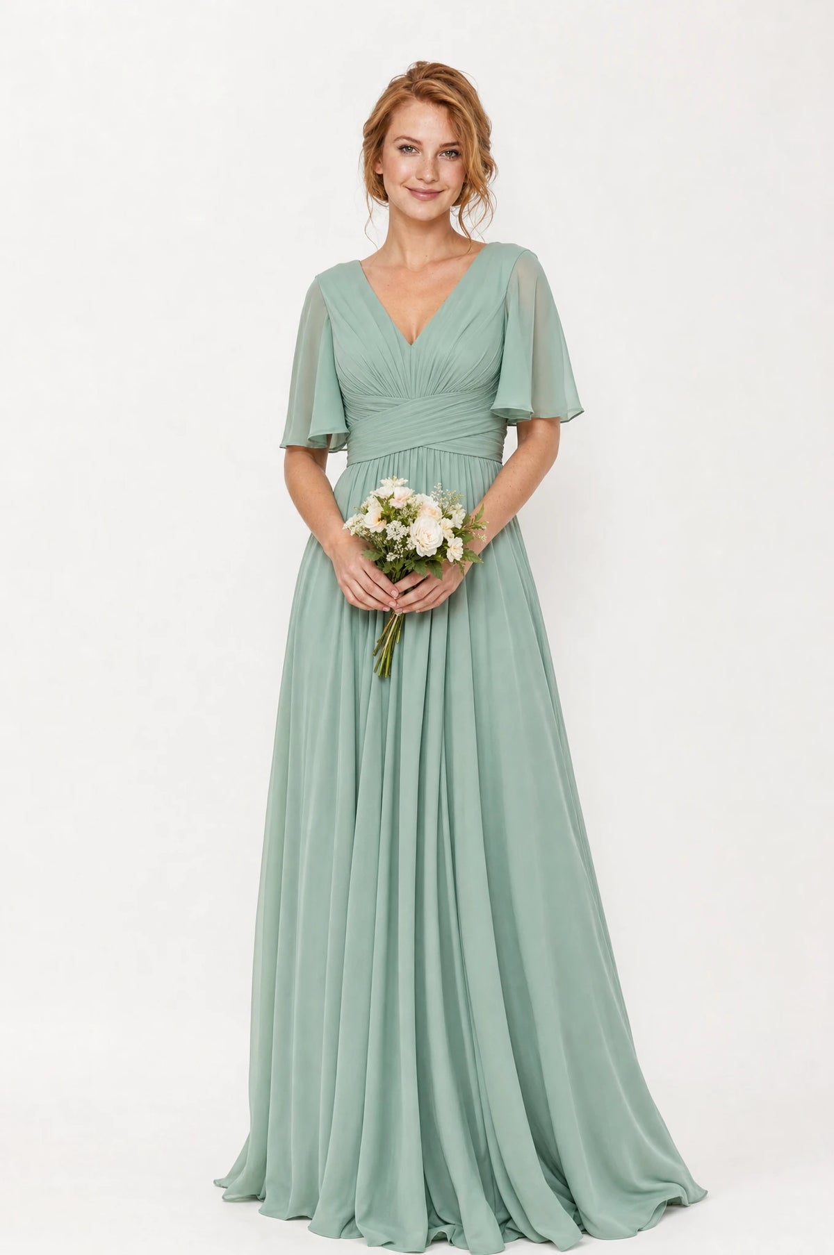 Robe demoiselle d'honneur longue fluide  vert sauge Rosalie portée de face par Julie cheveux roux ondulés, col en V, bodice plissé drapé, manches courtes évasées façon papillon, taille empire, jupe évasée fluide.