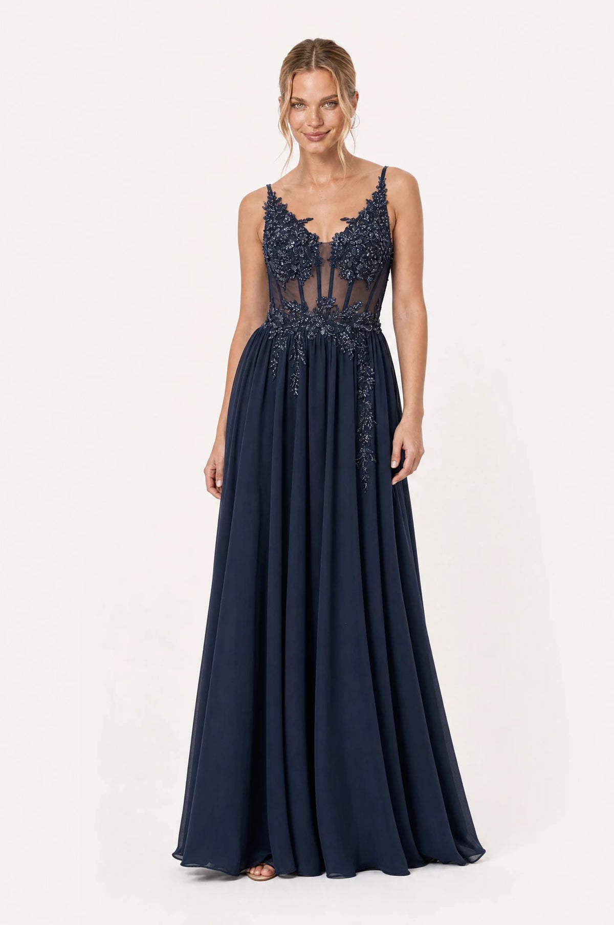 Robe de gala longue bleu marine Delphine portée de face par Aude chignon bas sleek, bustier en dentelle perlée sur tulle transparent, décolleté en V, fines bretelles, jupe évasée en mousseline au sol
