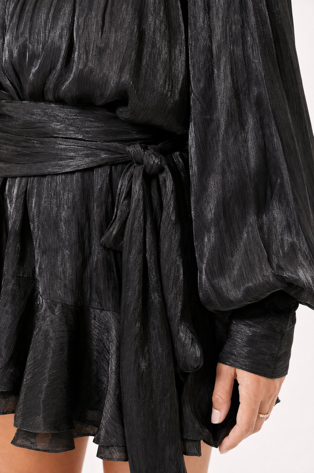 Gros plan sur le nœud de la ceinture et le tissu satiné froissé de la robe habillée noire Alix, détail des finitions