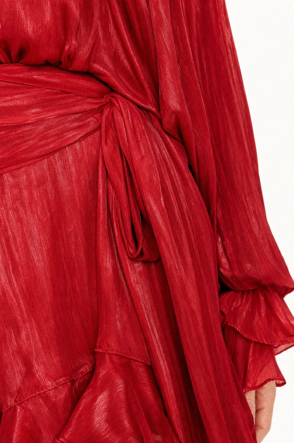 Gros plan sur le nœud de la ceinture et le tissu satiné froissé de la robe habillée rouge Tess, détail des finitions