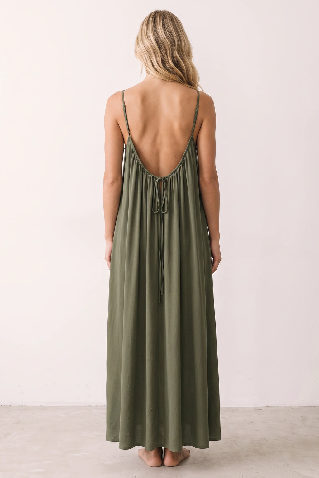Robe longue casual dos nu Ambre couleur Vert armé portée de dos par Chloé cheveux détachés, fines bretelles, dos ouvert arrondi avec petit détail bas du dos et coupe fluide sur fond clair