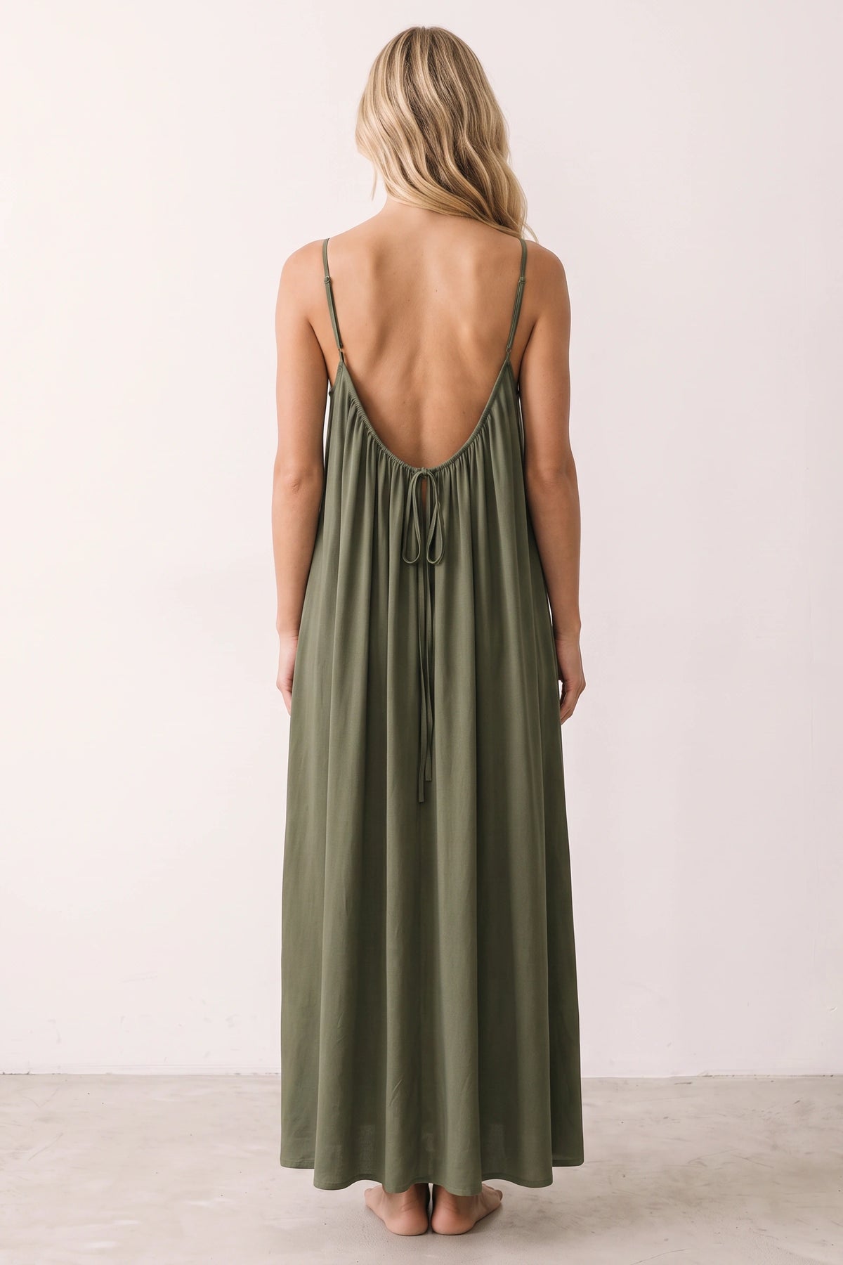 Robe longue casual dos nu Ambre couleur Vert armé portée de dos par Chloé cheveux détachés, fines bretelles, dos ouvert arrondi avec petit détail bas du dos et coupe fluide sur fond clair