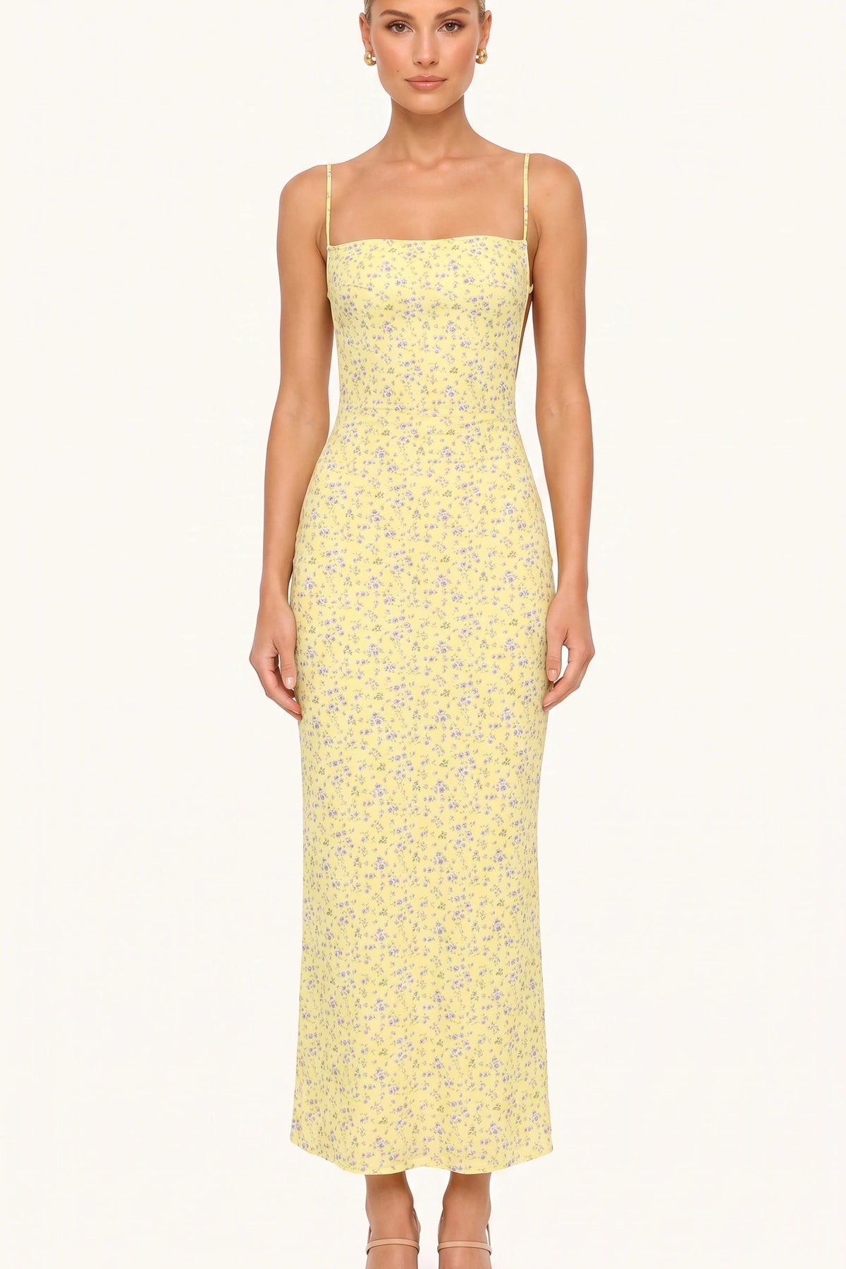 Robe moulante longue fleurie Livia jaune portée de face par Chloé, fines bretelles et coupe près du corps sur fond neutre clair