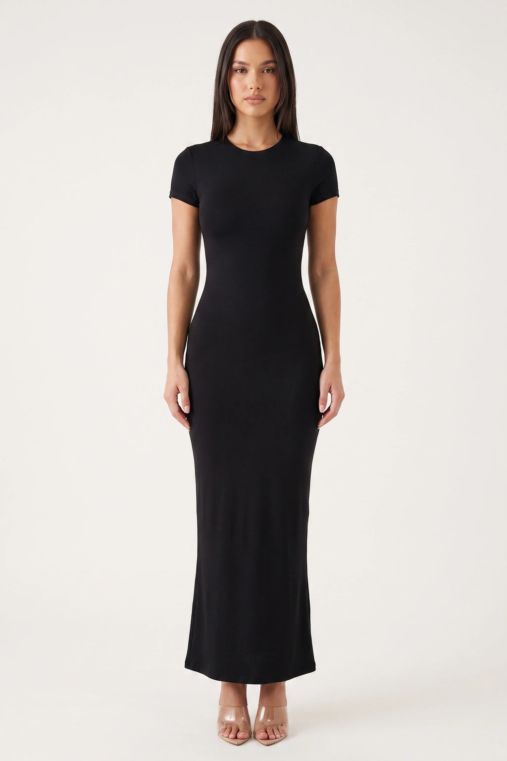 Robe moulante longue Mila noire portée de face par Camille sur fond neutre clair, col rond, manches courtes et coupe ajustée