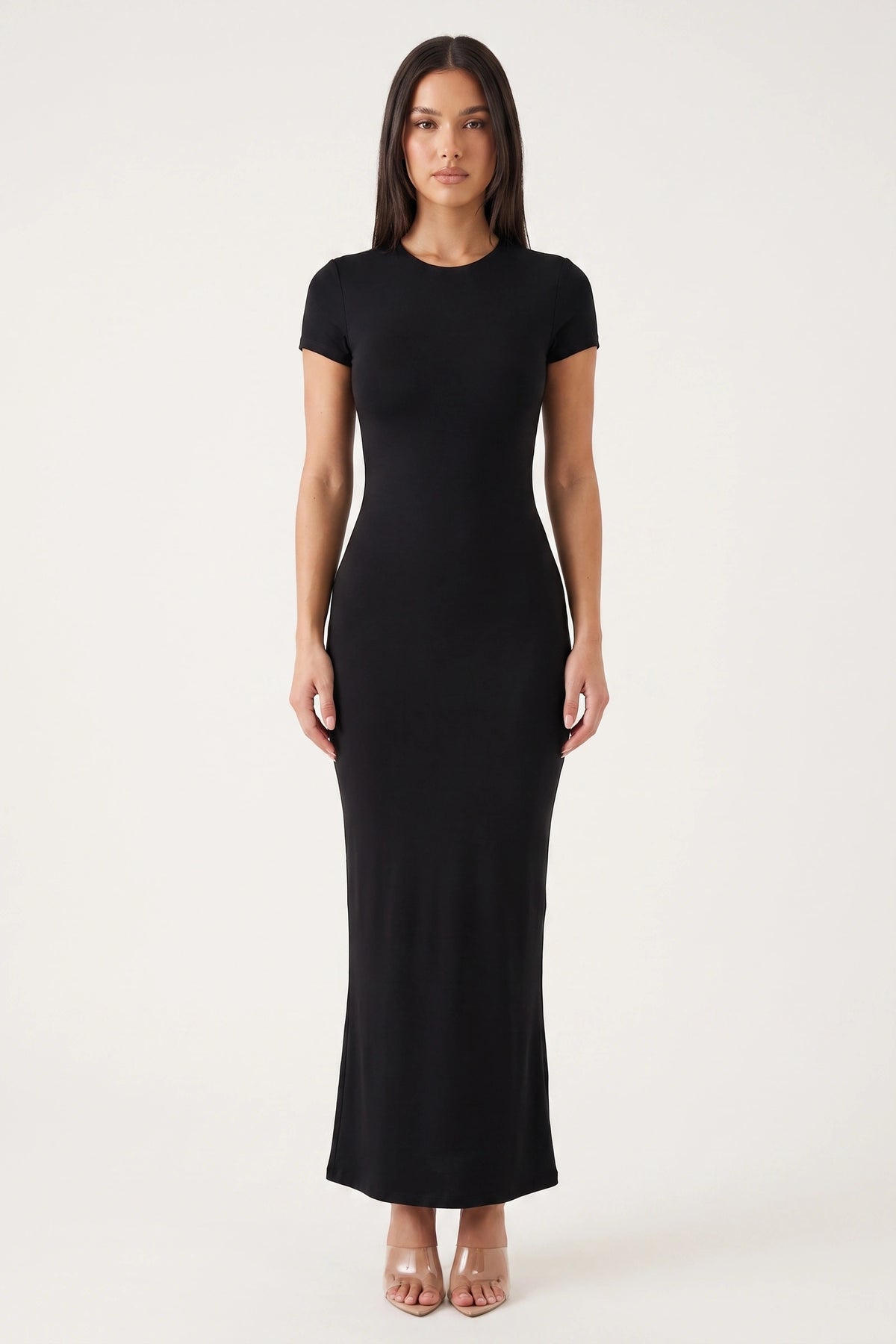 Robe moulante longue Mila noire portée de face par Camille sur fond neutre clair, col rond, manches courtes et coupe ajustée
