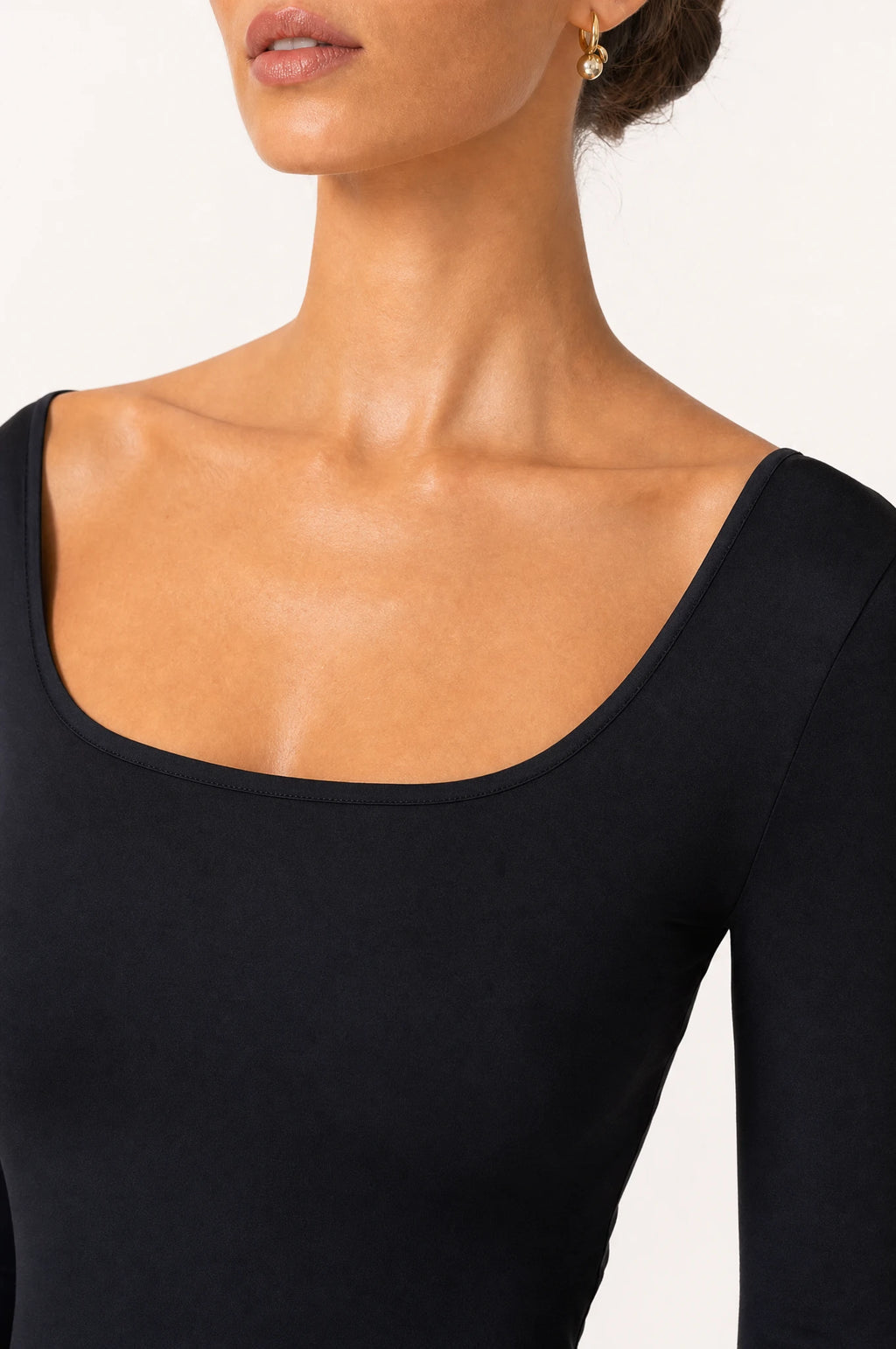 Gros plan encolure carrée et tissu lisse de la robe noire moulante Margaux, détail couture