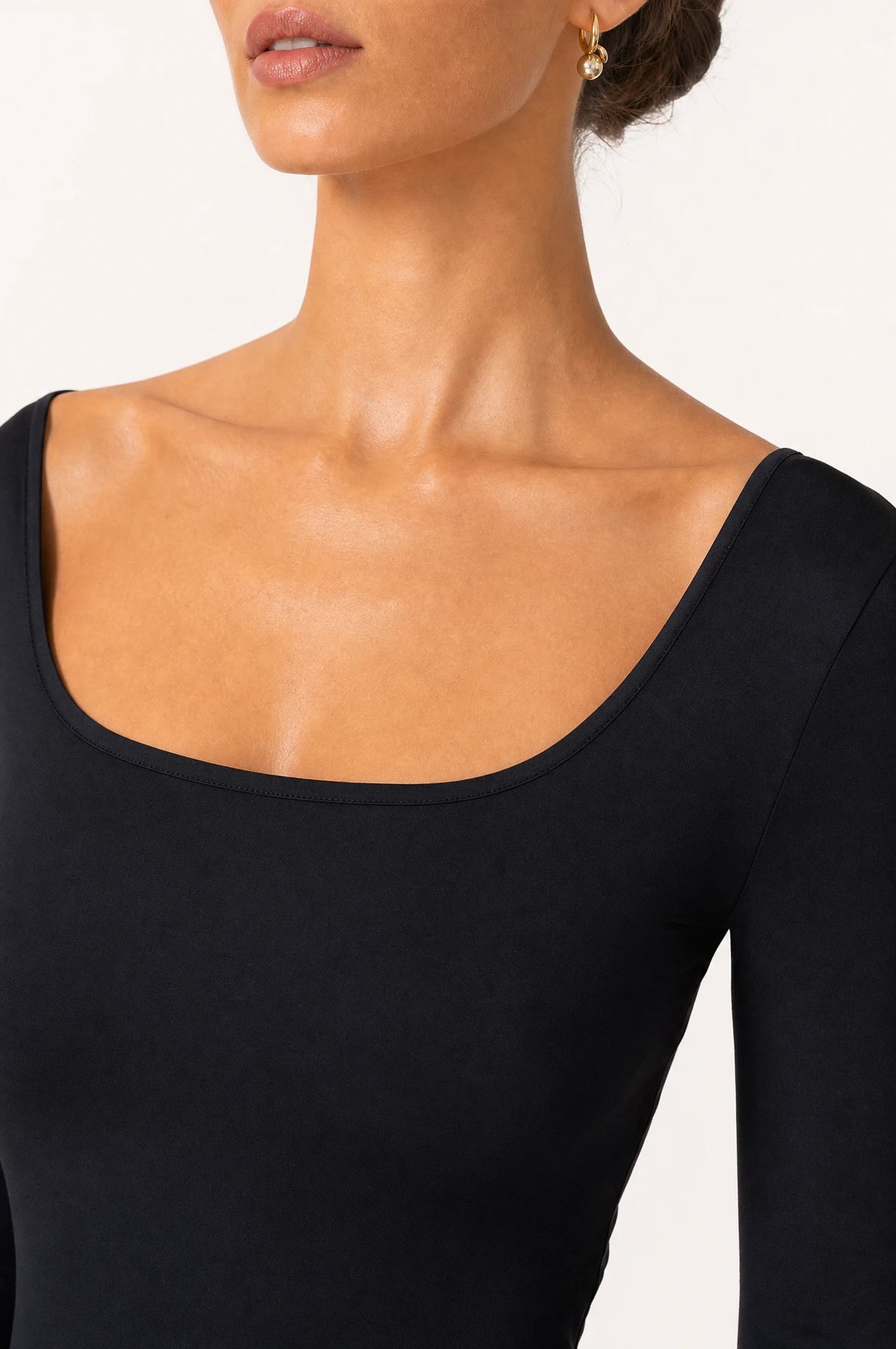 Gros plan encolure carrée et tissu lisse de la robe noire moulante Margaux, détail couture