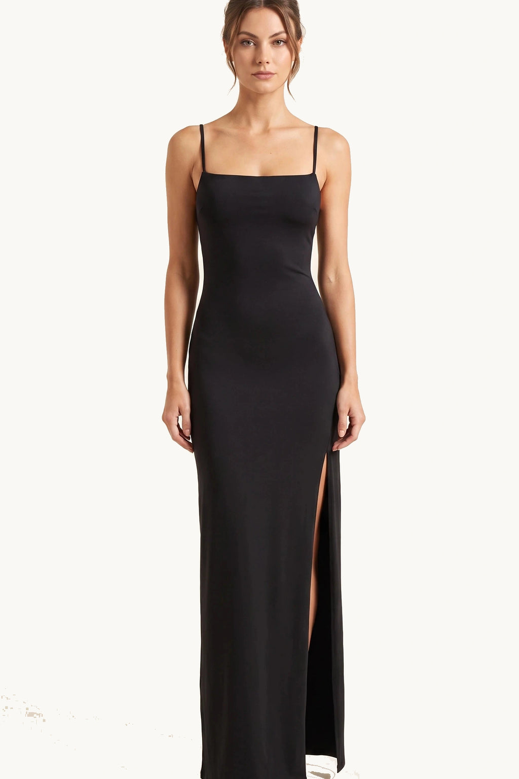 Robe sexy longue dos nu Selena noire portée de face par Élena, fines bretelles, coupe moulante et grande fente côté