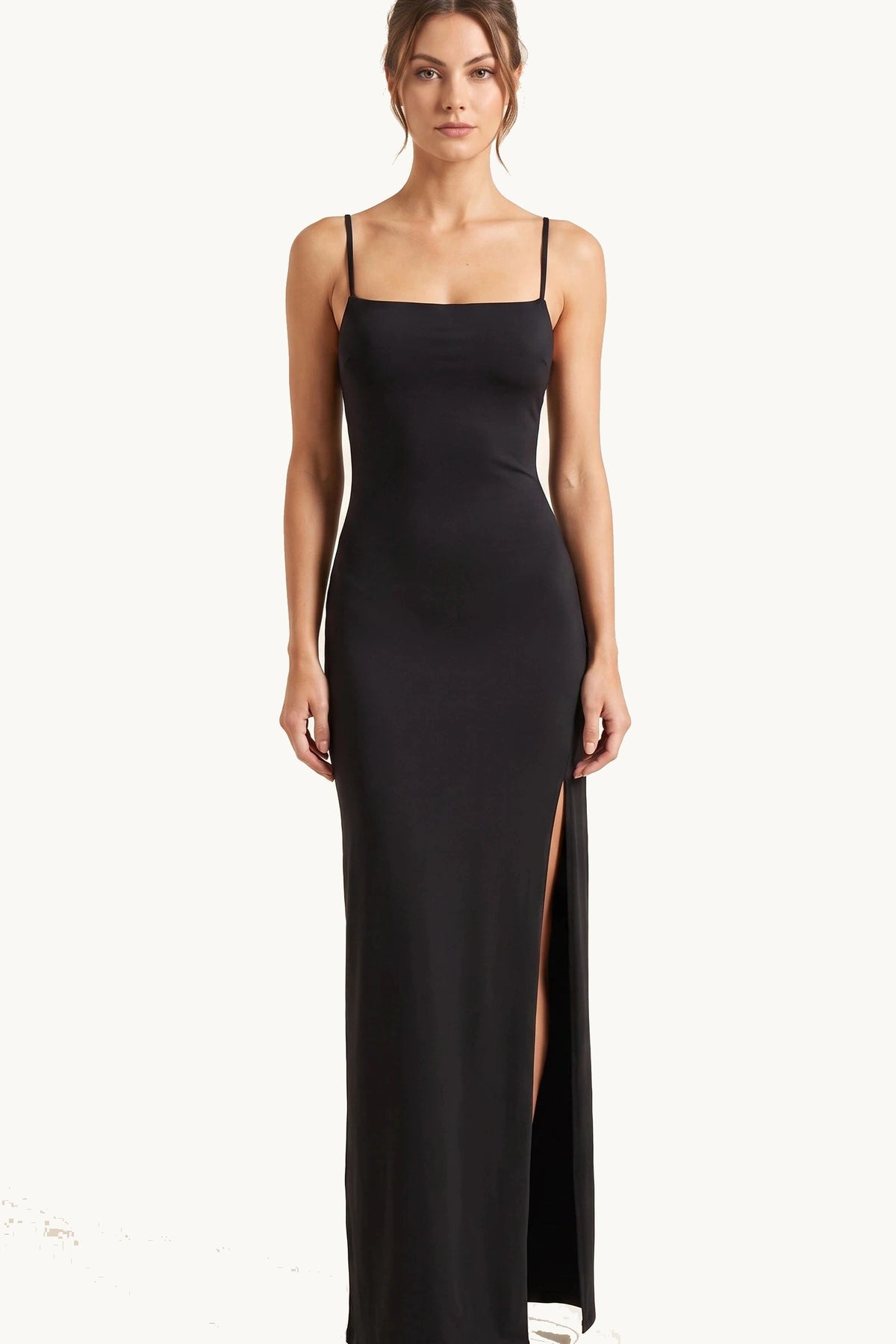 Robe sexy longue dos nu Selena noire portée de face par Élena, fines bretelles, coupe moulante et grande fente côté