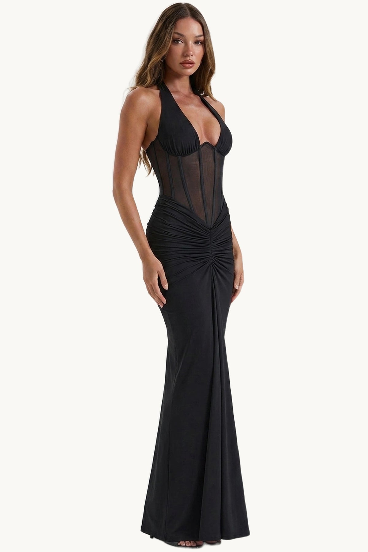 Robe sexy longue dos nu Mira noire studio face, fond studio neutre clair, portée par Camille cheveux détachés, robe longue noire halter à corsage transparent
