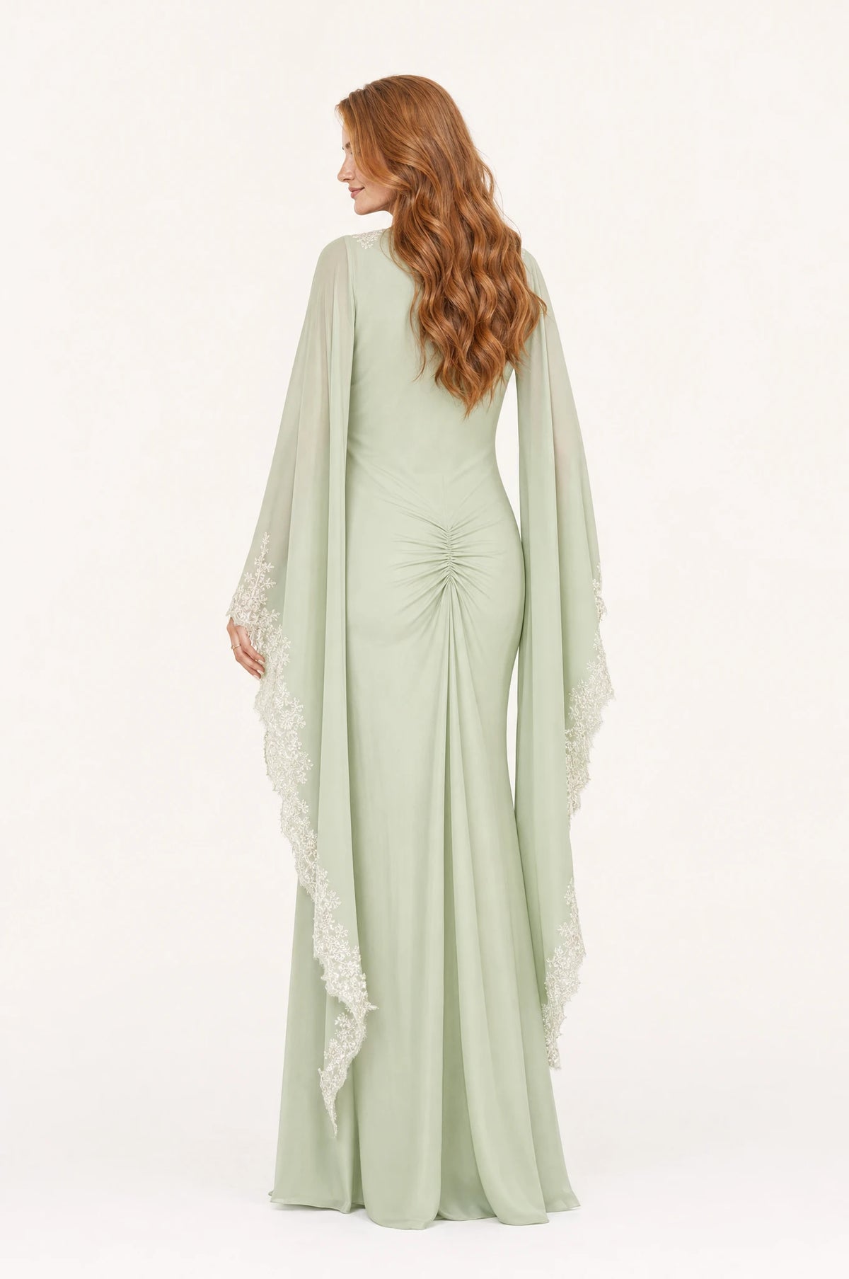 Dos de la robe sirène vert sauge Mathilde portée par Julie, dos uni avec fronce basse à la taille, manches amples drapées bordées de dentelle ivoire, coupe ajustée aux hanches, longueur au sol