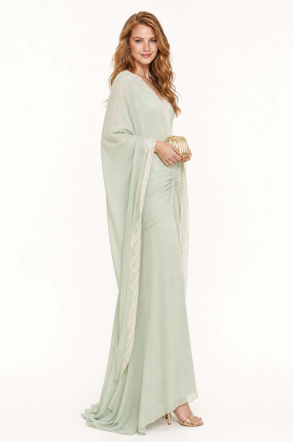 Robe sirène vert sauge Mathilde vue de profil portée par Julie, manches drapées bordées de dentelle ivoire, taille froncée, coupe ajustée évasée vers l'ourlet, longueur au sol
