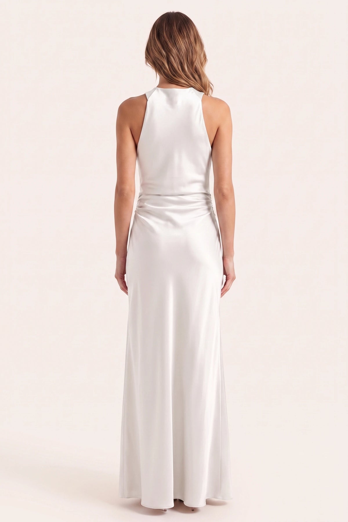 Robe de soirée satinée Élena blanche portée de dos sur fond neutre clair, nuque et col licou corrigés, tombé fluide pour cérémonie chic