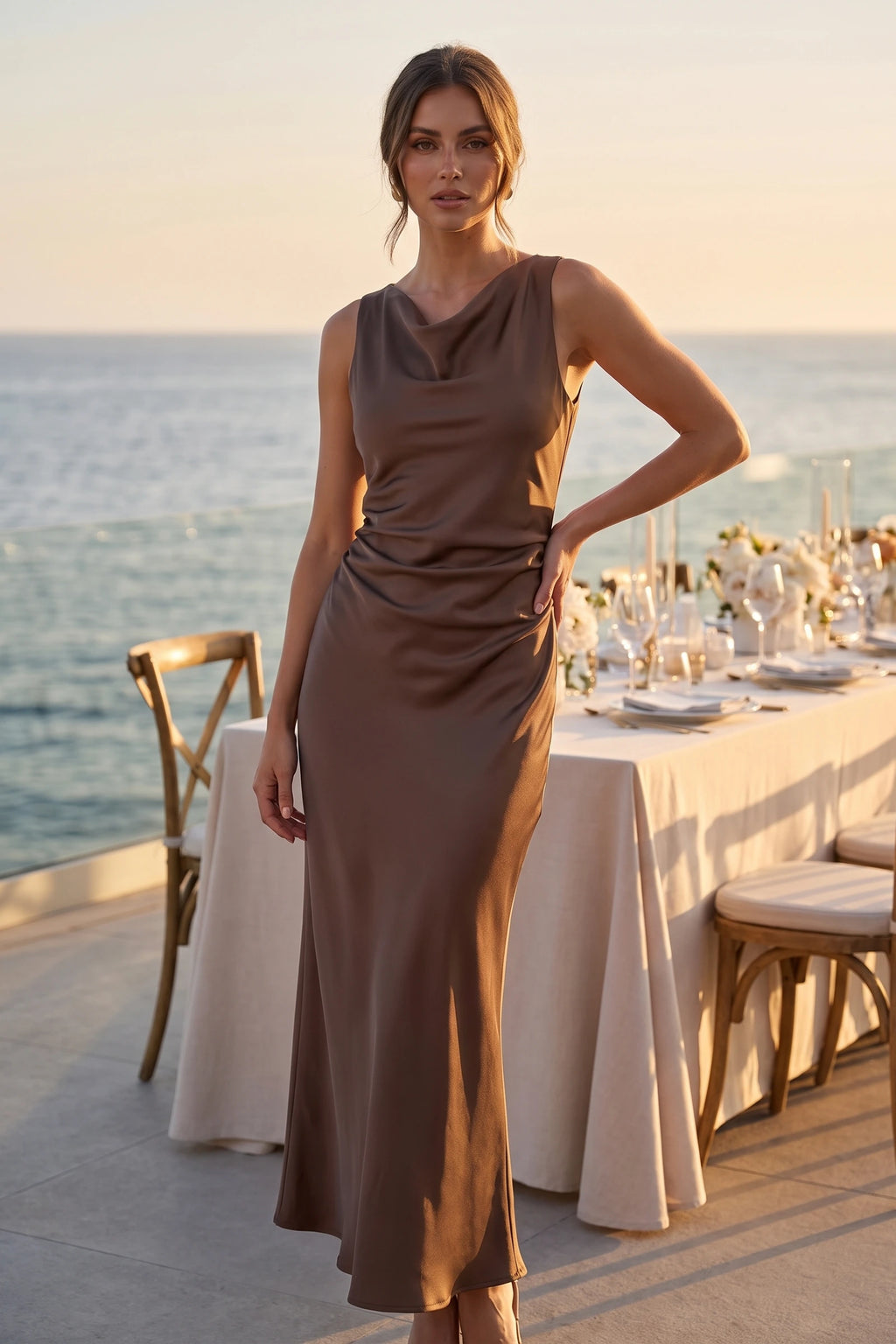 Robe de soirée satinée Élena marron portée en dîner bord de mer, tissu satiné, col licou et coupe longue raffinée