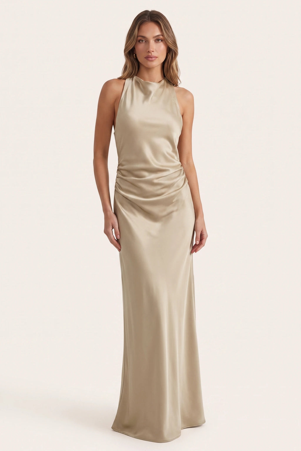 Robe de soirée satinée Élena beige portée de face par le Mannequin Élena sur fond neutre clair, col licou sans manches, drapé chic et coupe longue fluide pour soirée élégante