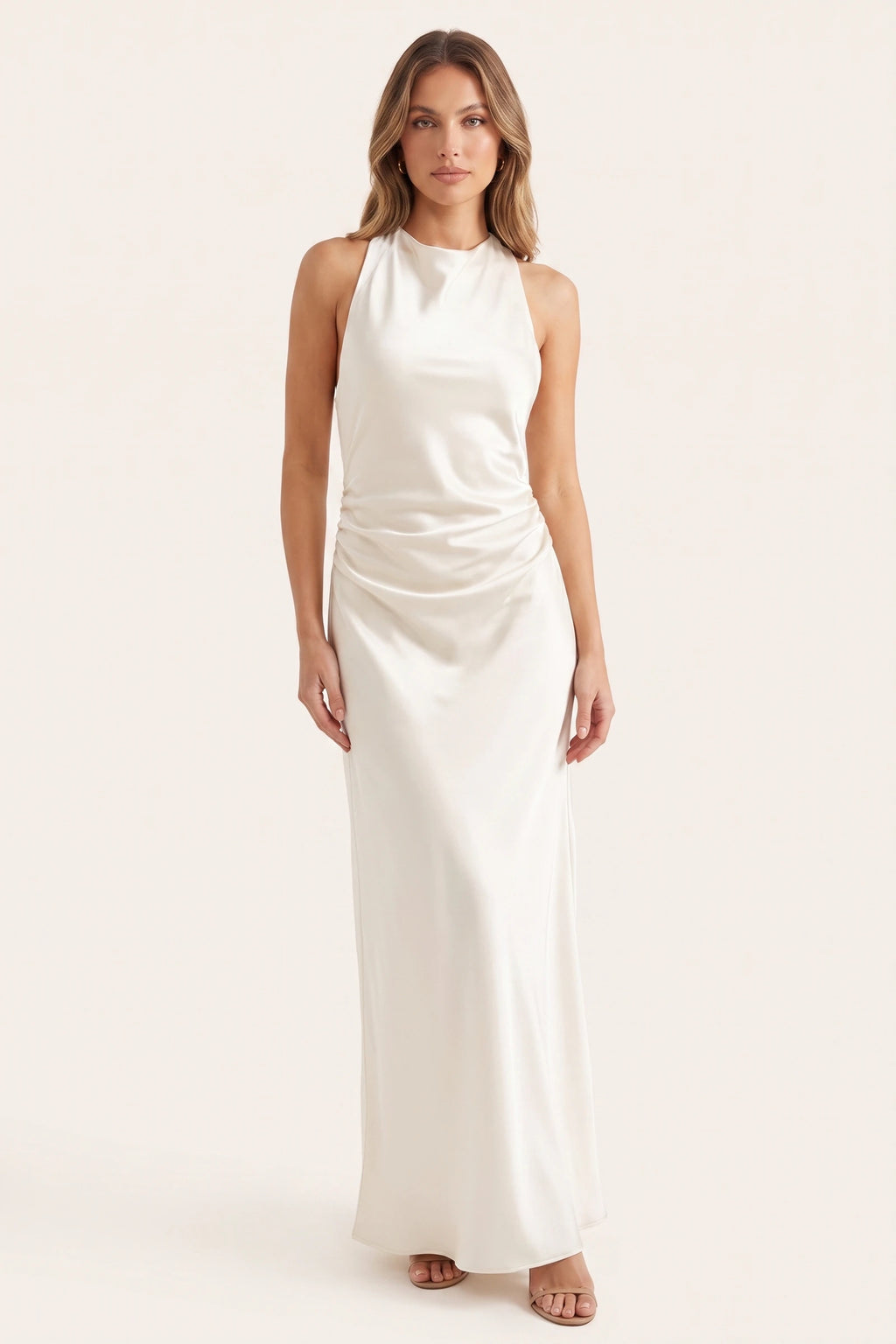 Robe de soirée satinée Élena blanche portée de face par le Mannequin Élena sur fond neutre clair, col licou, coupe longue lumineuse et drapé raffiné