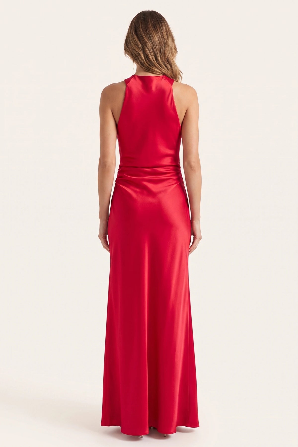 Robe de soirée satinée Élena rouge portée de dos sur fond neutre clair, dos licou non inventé, coupe longue fluide et allure de soirée affirmée