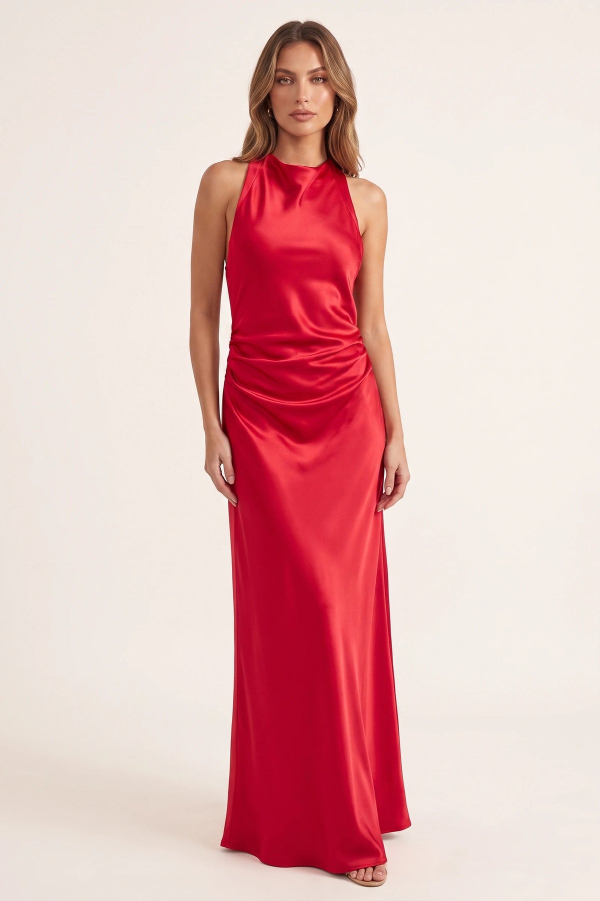 Robe de soirée satinée Élena rouge portée de face par le Mannequin Élena sur fond neutre clair, col licou, drapé lumineux et présence glamour