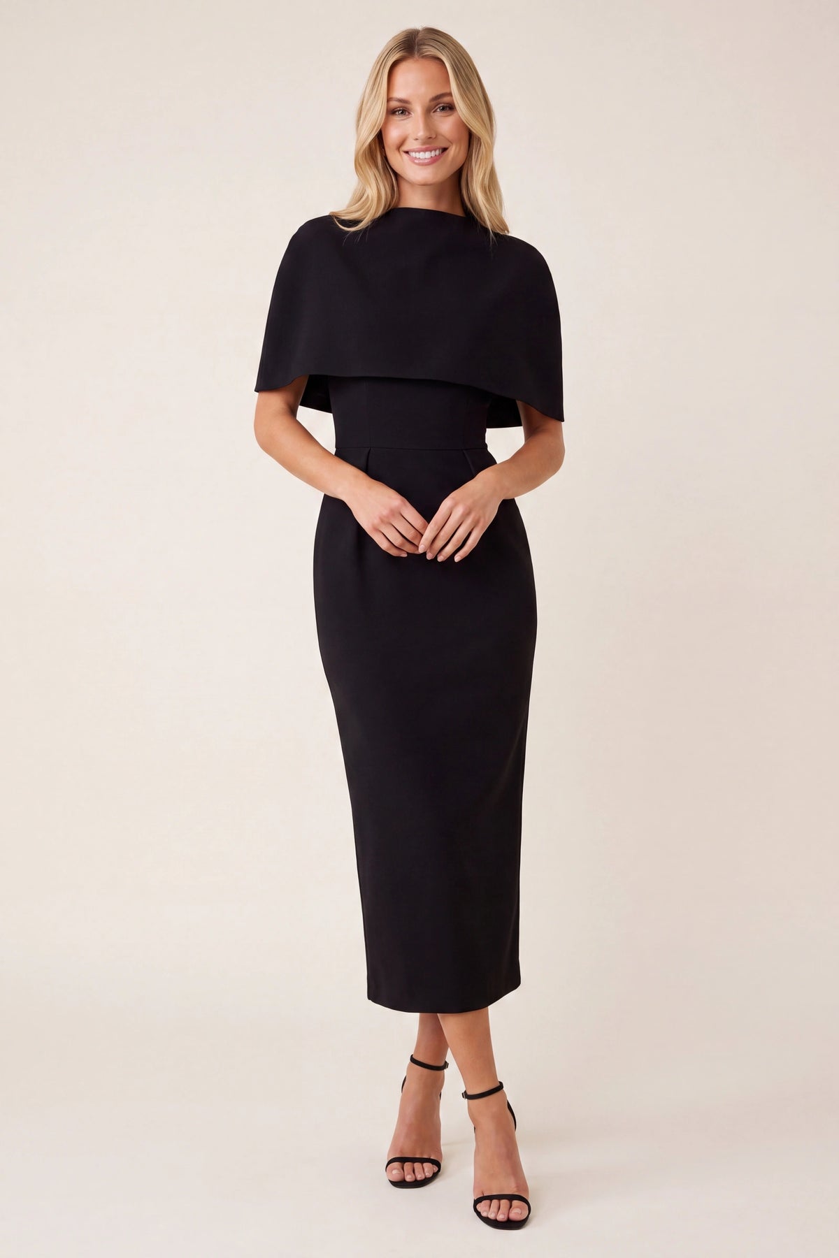 Robe tailleur femme Alice noire portée de face par la mannequin Chloé, coupe midi chic, cape structurée, col haut et silhouette élégante sur fond beige ivoire fond neutre clair, parfaite pour soirée et événement habillé.