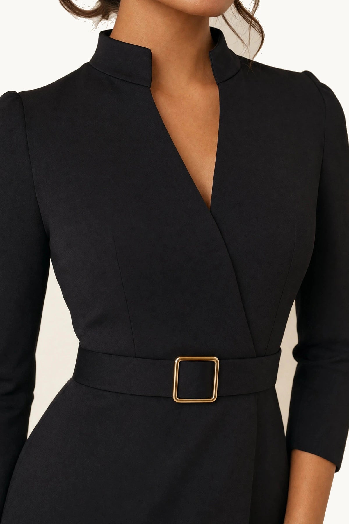 Détail de la robe tailleur noire Diane avec col montant ouvert en V, tissu noir structuré et ceinture à boucle carrée dorée, zoom mode chic pour fiche produit.