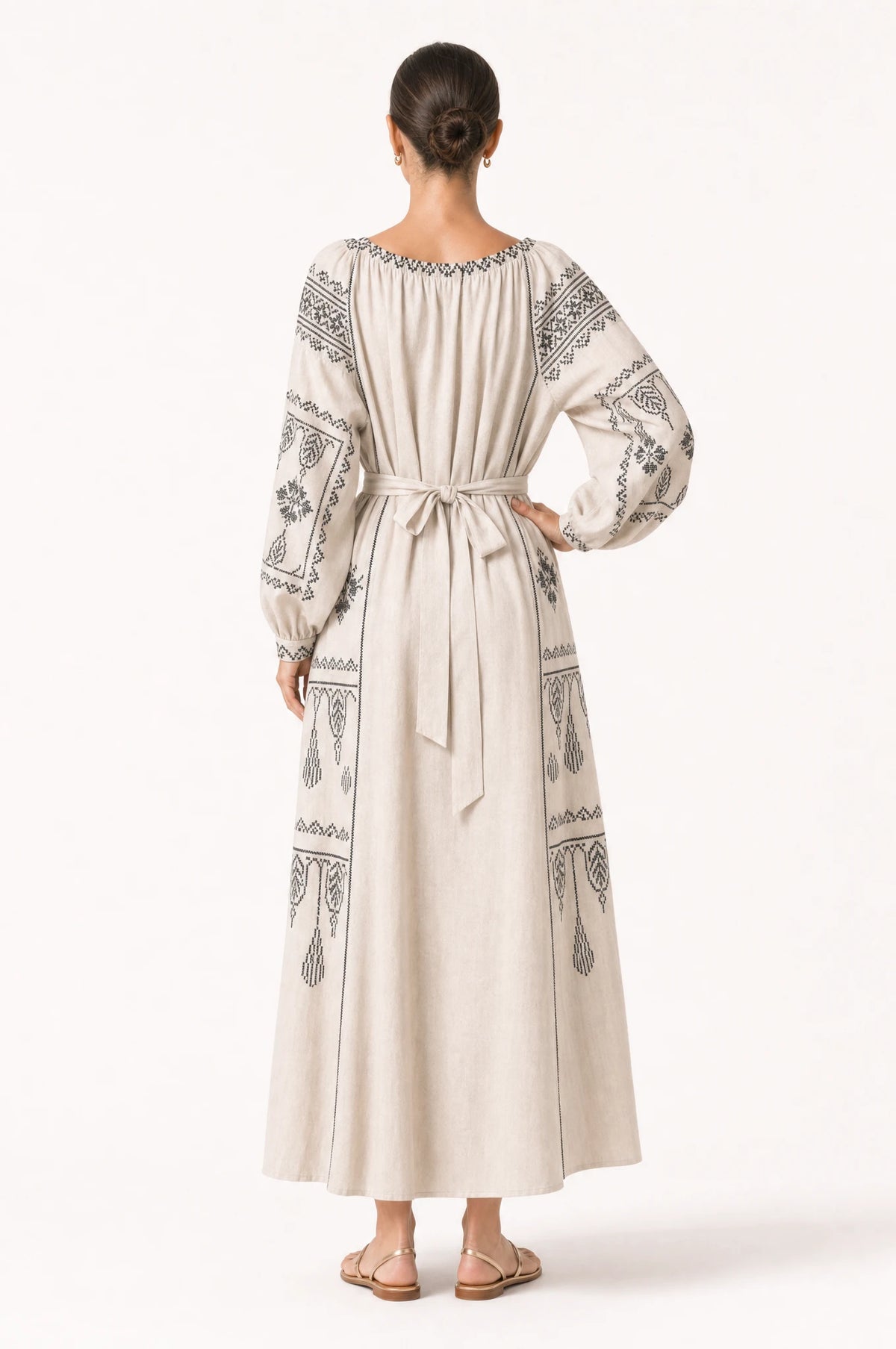 Robe vintage brodée beige Elsa portée de dos par Nath, panneaux brodés ethniques noirs sur les épaules et les manches, ceinture nouée dans le dos, jupe évasée fluide