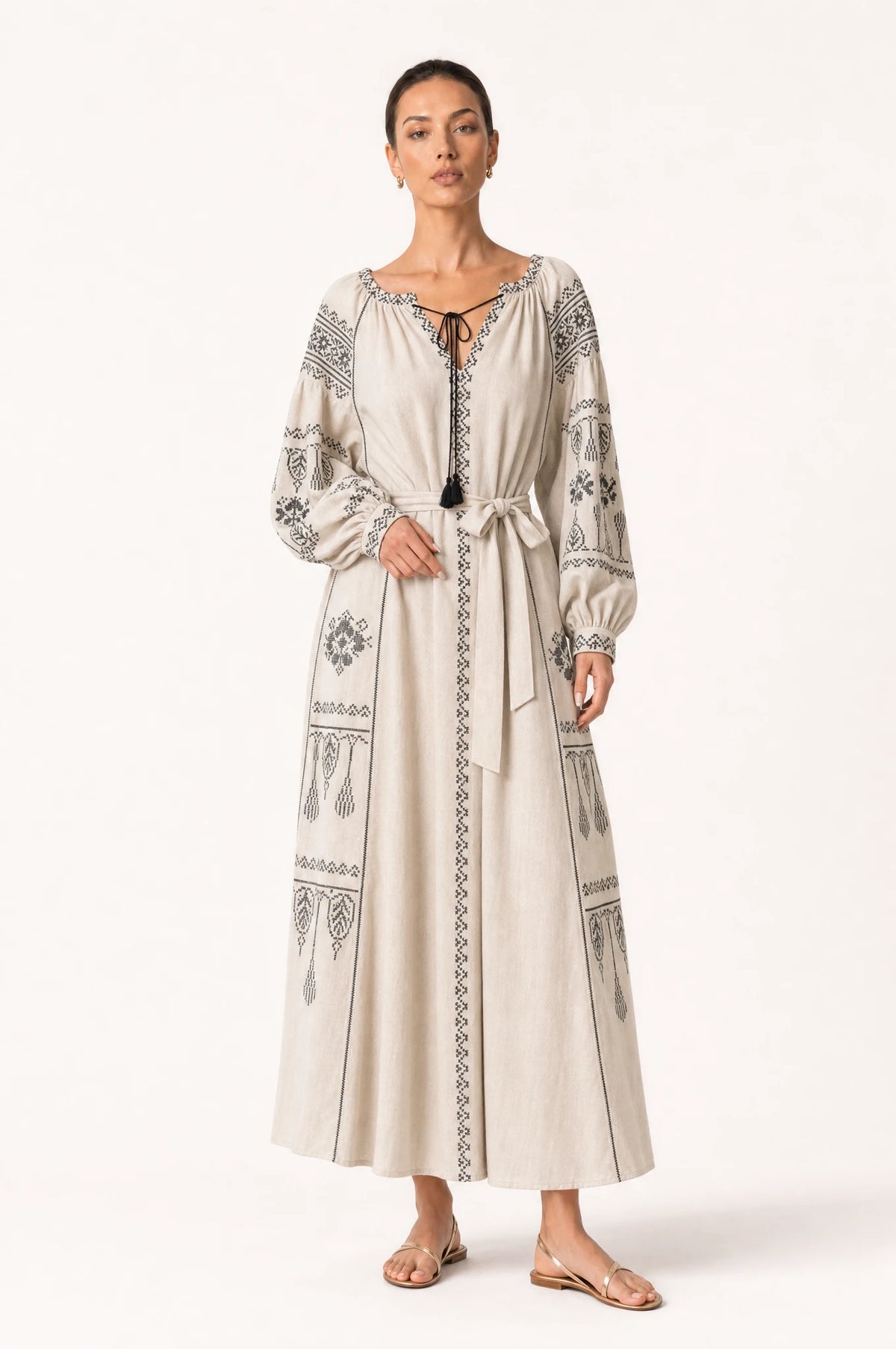 Robe vintage brodée beige Elsa portée de face par Nath, décolleté rond fermé par un lacet noué, broderie ethnique noire sur les manches bouffantes et la jupe, ceinture nouée à la taille, style folk chic intemporel