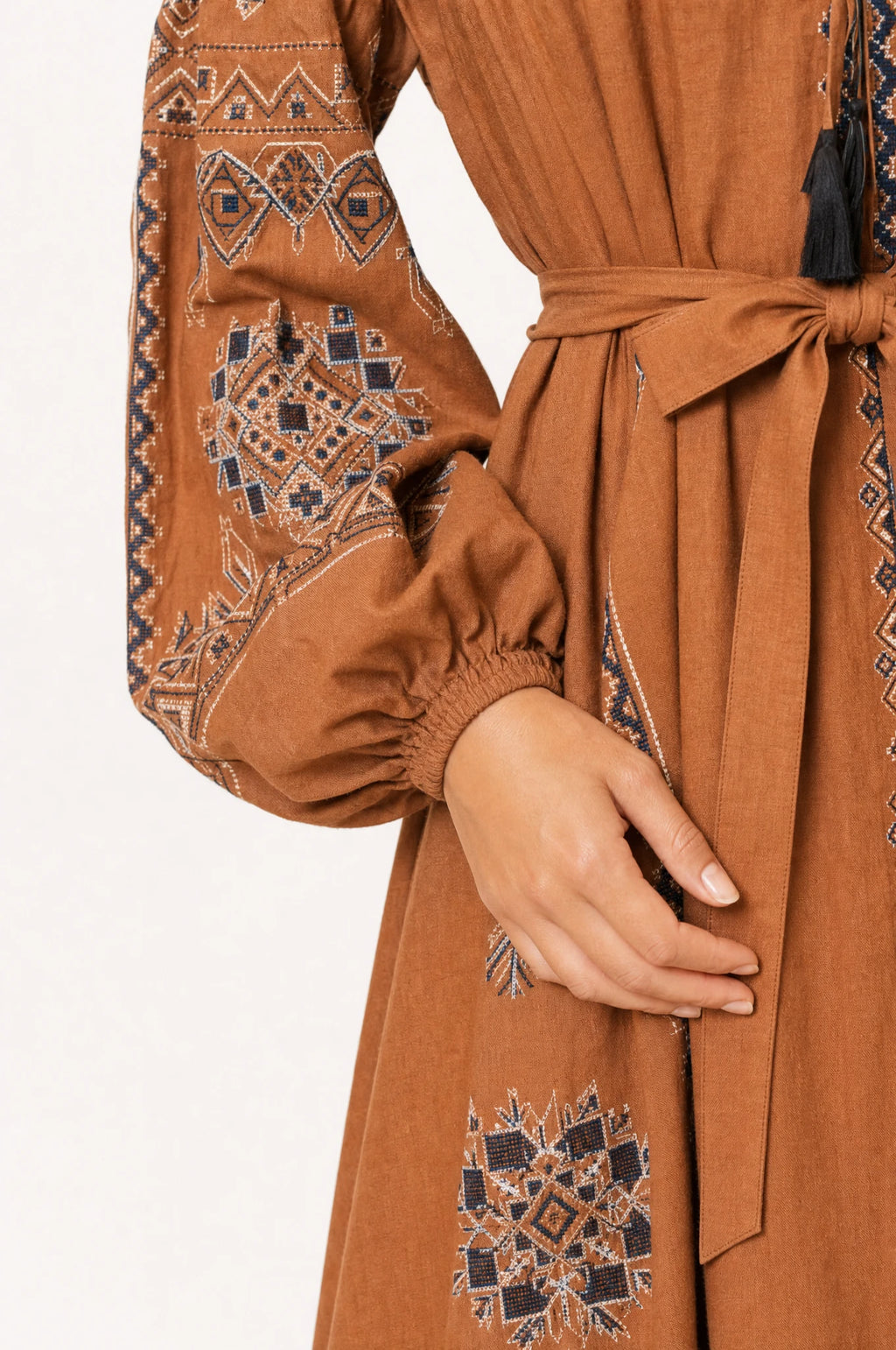 Gros plan sur les broderies ethniques et la ceinture nouée de la robe vintage marron Margot, détail des manches bouffantes resserrées et du tissu coton lin