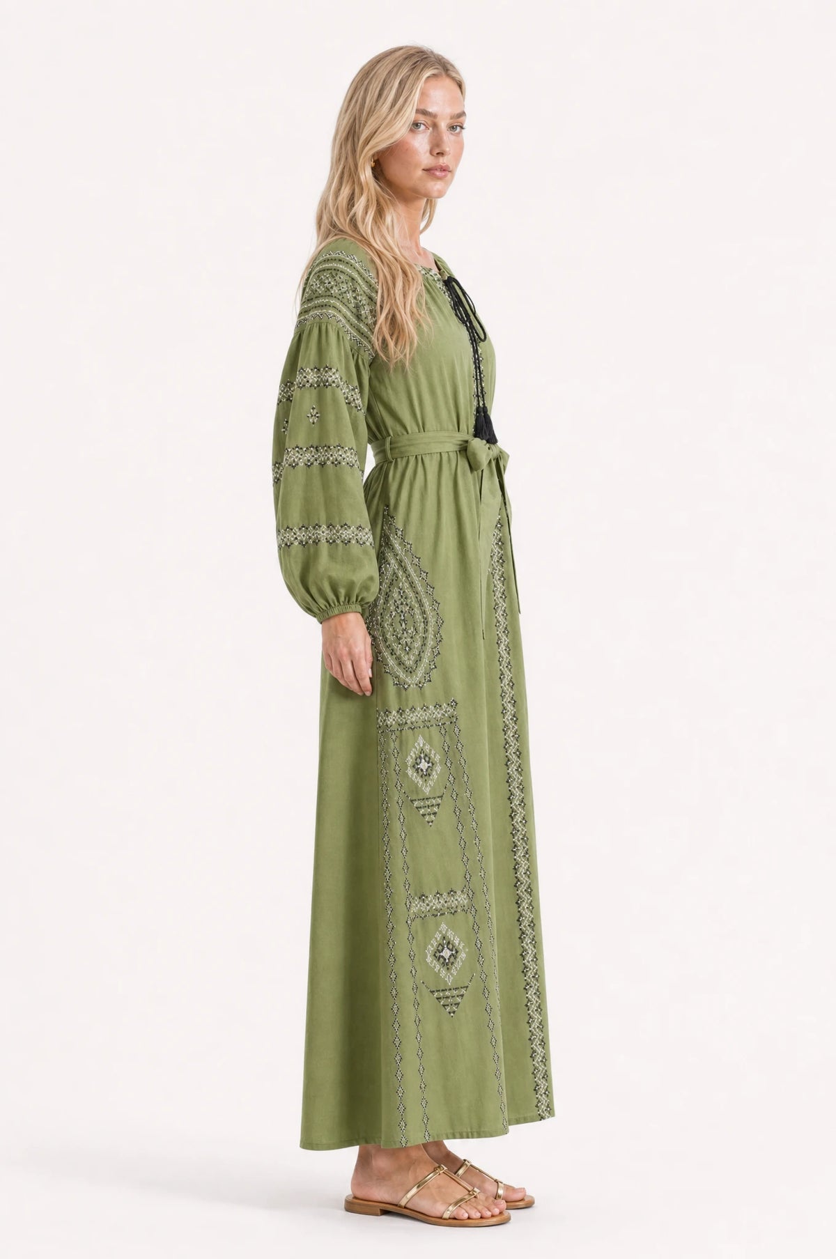 Robe vintage brodée Romane vue de profil portée par Sophie, silhouette évasée coupe empire, broderie noir et blanc, jupe longue jusqu'aux chevilles, ceinture nouée à la taille