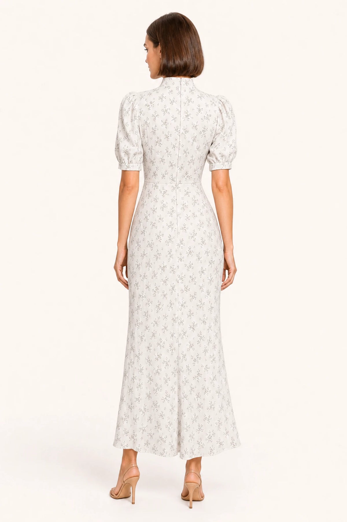 Dos de la robe vintage fleurie blanche Clémence portée par Élodie, col montant continuant dans le dos, fermeture zippée visible, manches courtes bouffantes, jupe fourreau longueur cheville