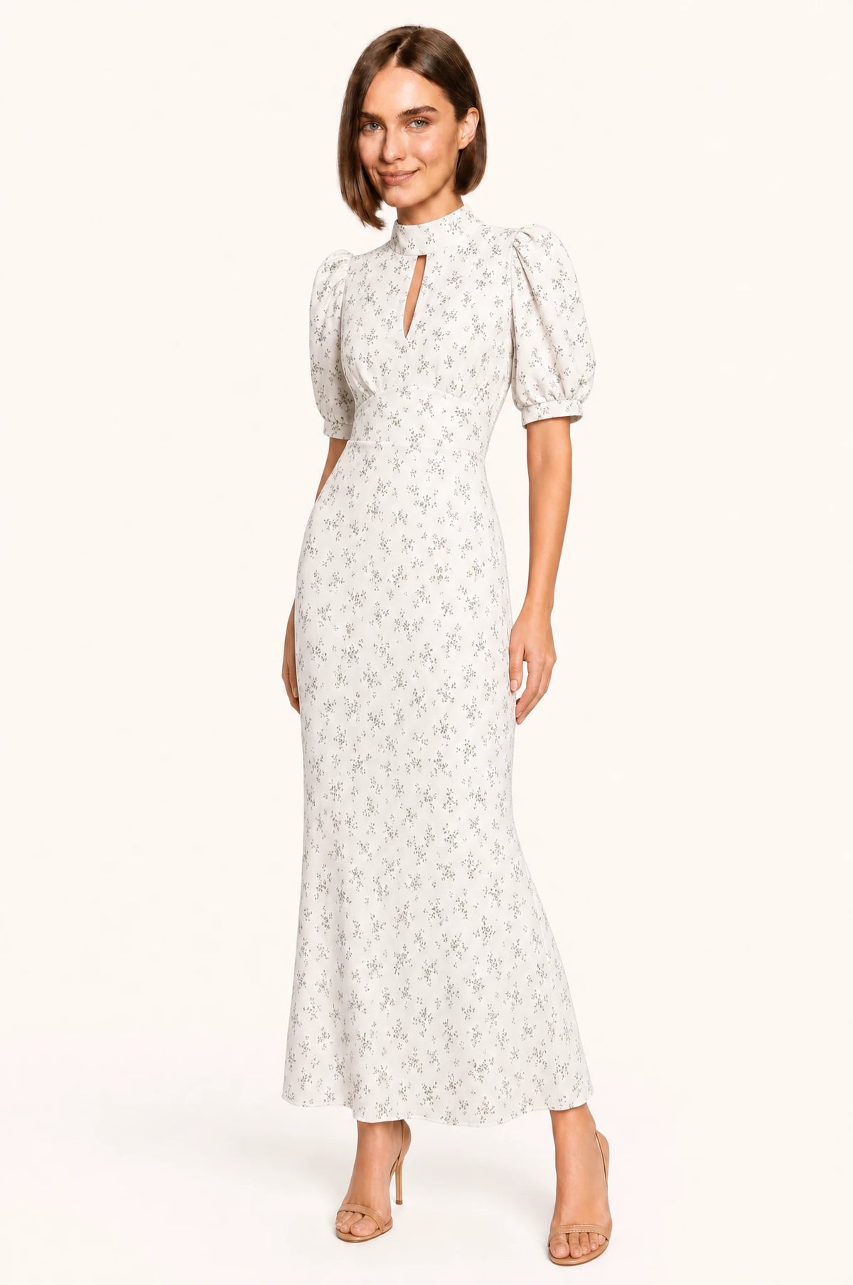 Robe vintage fleurie blanche Clémence portée de face par Élodie, col montant fermé avec petite découpe en goutte sous la gorge, manches courtes bouffantes, taille marquée, jupe fourreau longueur cheville