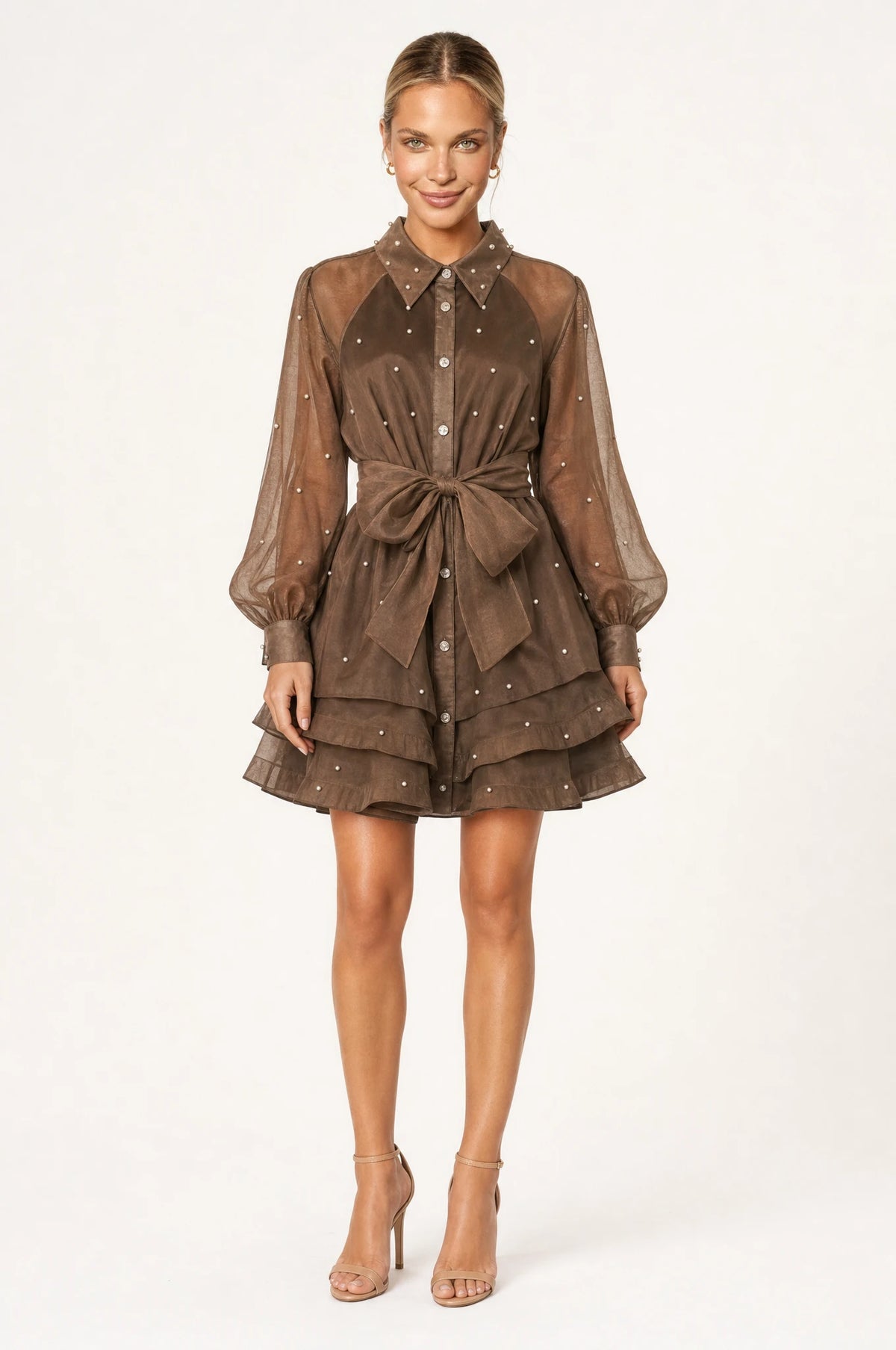 Robe vintage perlée kaki Colette portée de face par Aude chignon sleek, col chemisier structuré, boutons perlés et strass sur le buste, manches bouffantes en organza semi-transparent, ceinture nouée à la taille, jupe courte à volants superposés