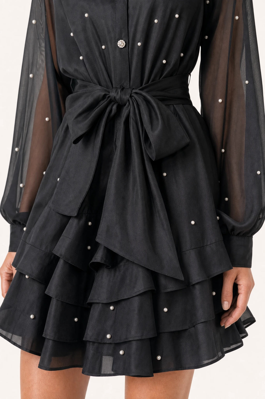 Gros plan sur la ceinture nouée et la jupe à volants perlée de la robe vintage noire Héloïse, détail des perles et strass sur le tissu organza et satin