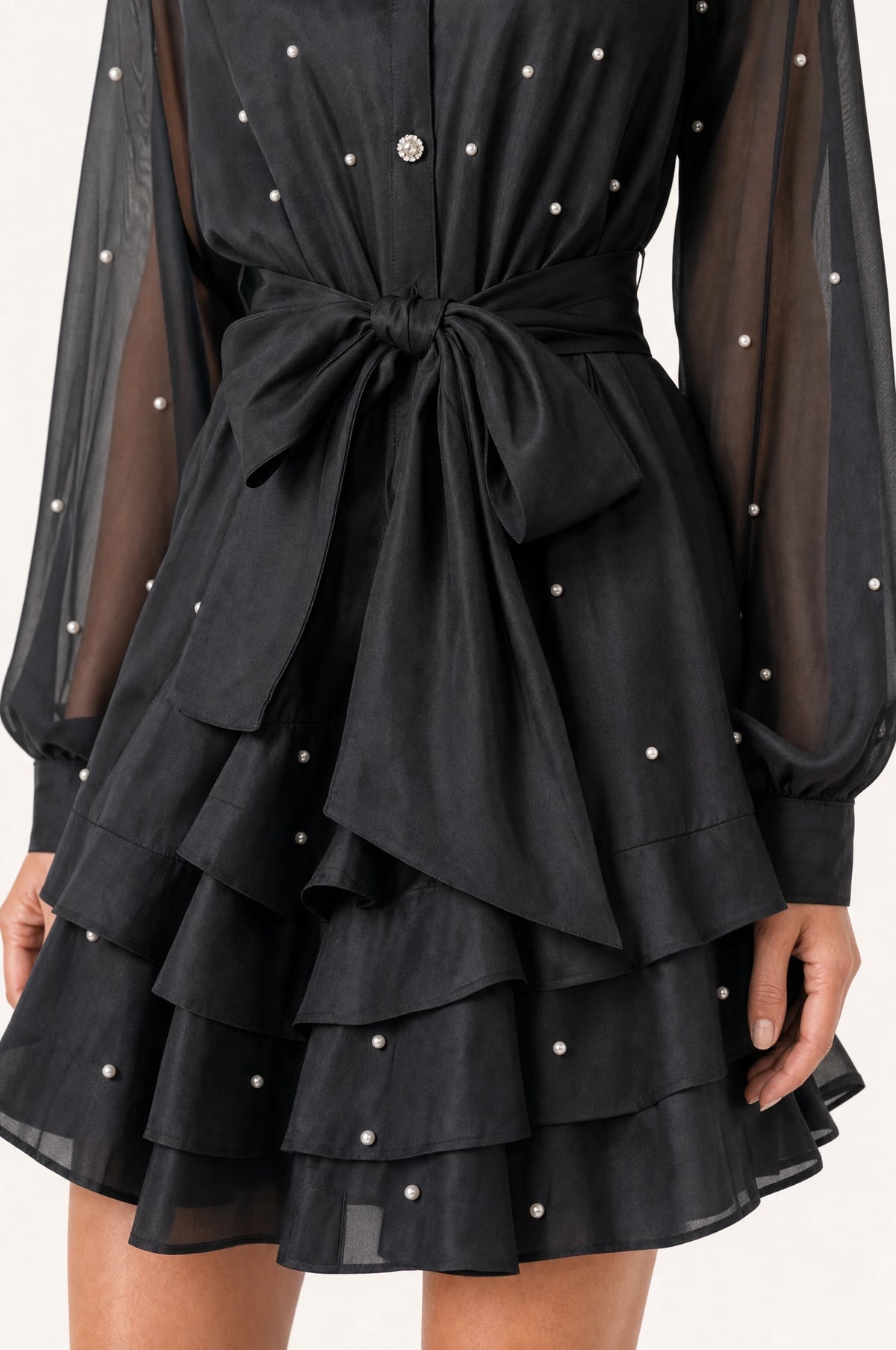 Gros plan sur la ceinture nouée et la jupe à volants perlée de la robe vintage noire Héloïse, détail des perles et strass sur le tissu organza et satin
