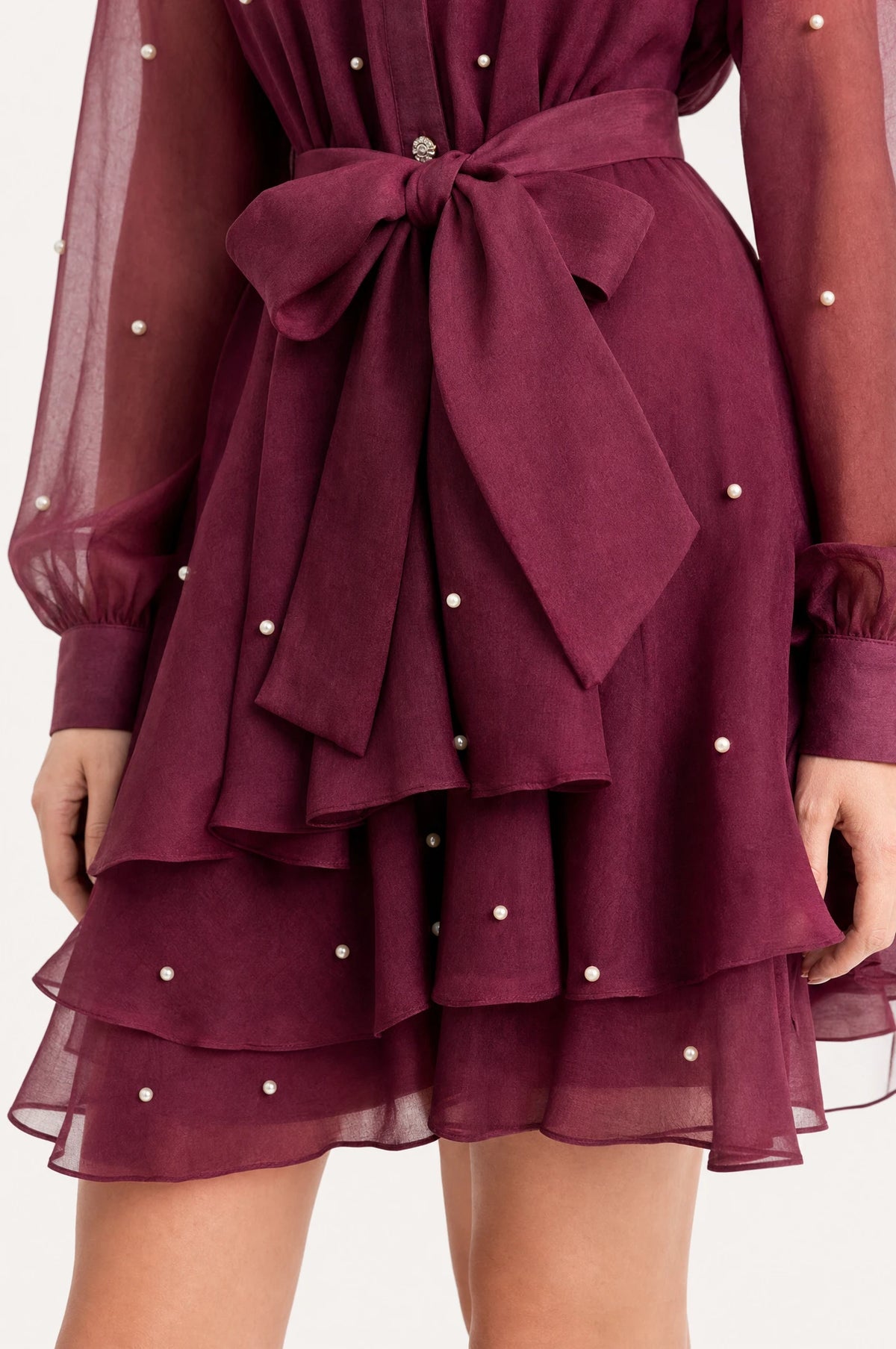 Gros plan sur la ceinture nouée et la jupe à volants perlée de la robe vintage rouge grenat Garance, détail des perles et strass sur le tissu organza et satin