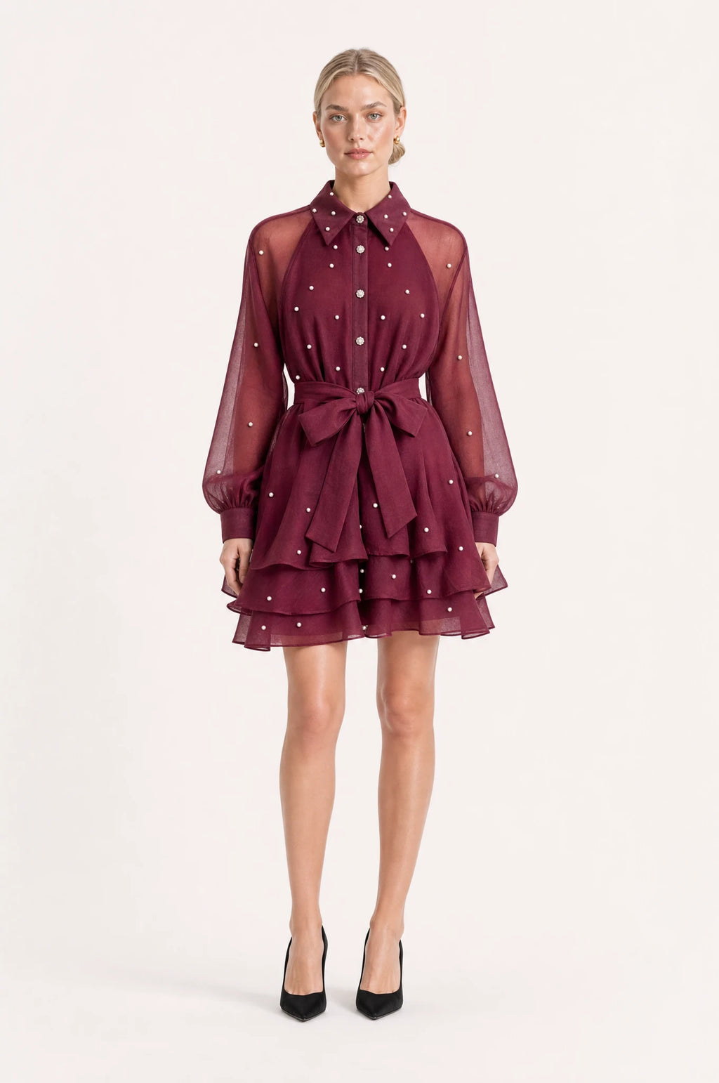 Robe vintage perlée rouge grenat Garance portée de face par Sophie chignon sleek, col chemisier structuré, boutons perlés et strass sur le buste, manches bouffantes en organza semi-transparent, ceinture nouée à la taille, jupe courte à volants superposés