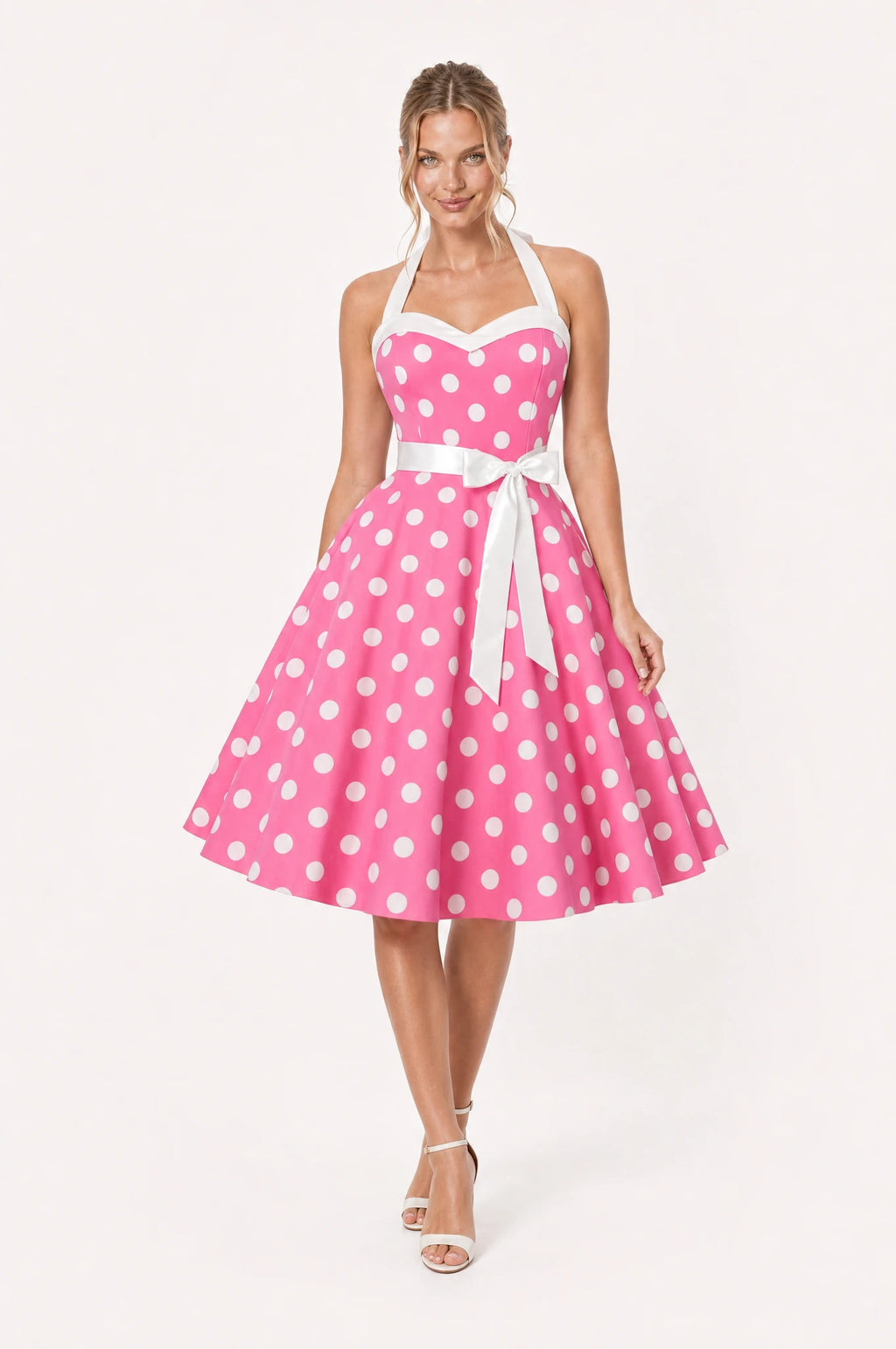 Robe Année 50 rose à pois Simone portée de face par Aude chignon bas sleek, col halter noué derrière la nuque, bustier en cœur bordé de blanc, ceinture blanche nouée en nœud, jupe en corolle plissée au genou