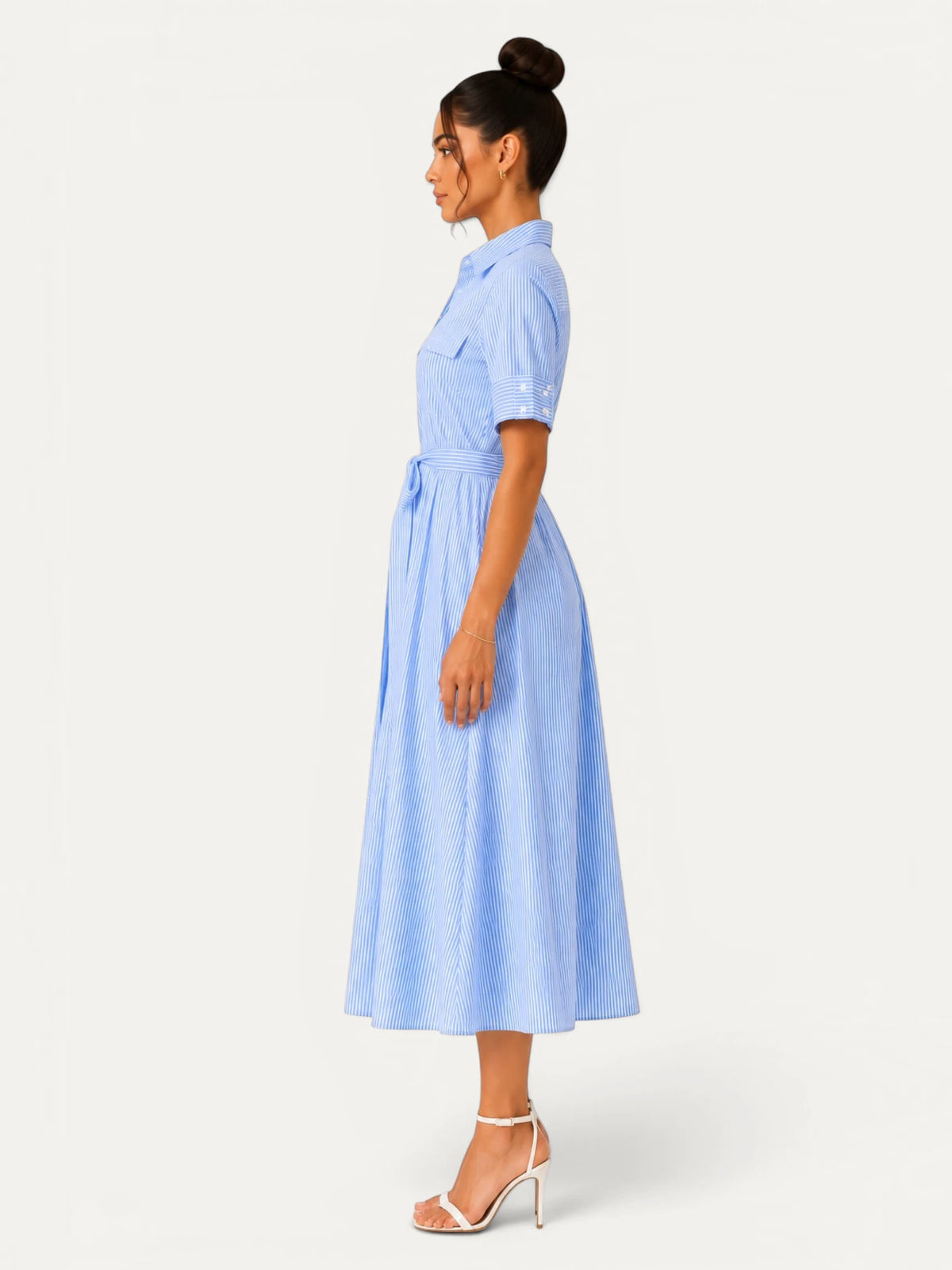 Profil d’une robe chemise longue bleu clair à rayures verticales, dotée d’une taille marquée et d’une jupe ample, idéale pour un style casual chic moderne.