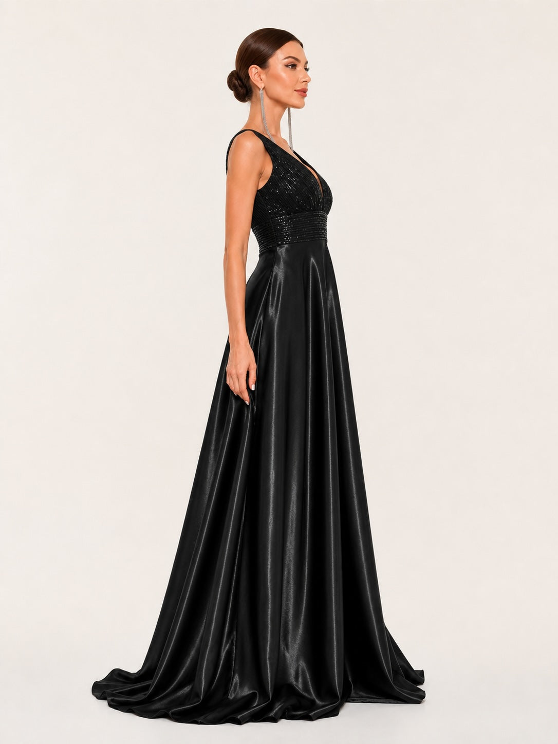 Profil élégant d’une robe de gala noire à coupe évasée, mettant en valeur la taille marquée et la fluidité luxueuse du tissu satiné.
