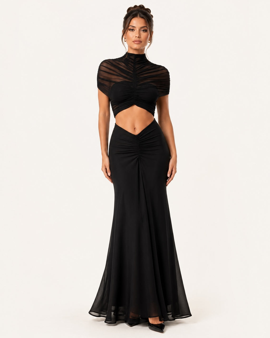 Silhouette glamour en robe de soirée noire ajustée, associant transparence subtile, taille découpée et jupe longue fluide pour un look sophistiqué et tendance.