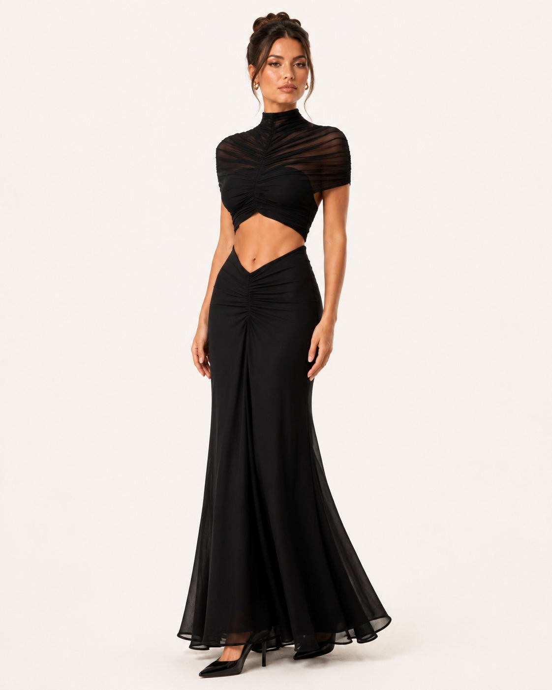 Vue trois quarts d’une robe maxi noire élégante avec effet drapé, taille ajourée et jupe fluide évasée, mettant en valeur une silhouette féminine et raffinée.