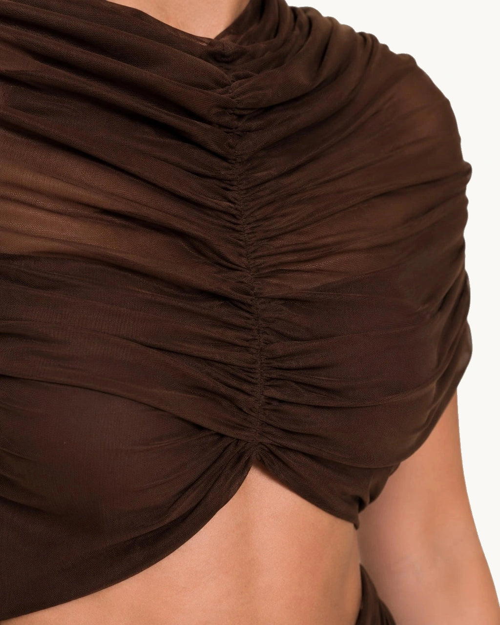 Détail du corsage froncé en maille transparente marron foncé, mettant en valeur le travail de drapé et la finition haut de gamme d’une robe de cérémonie moderne.